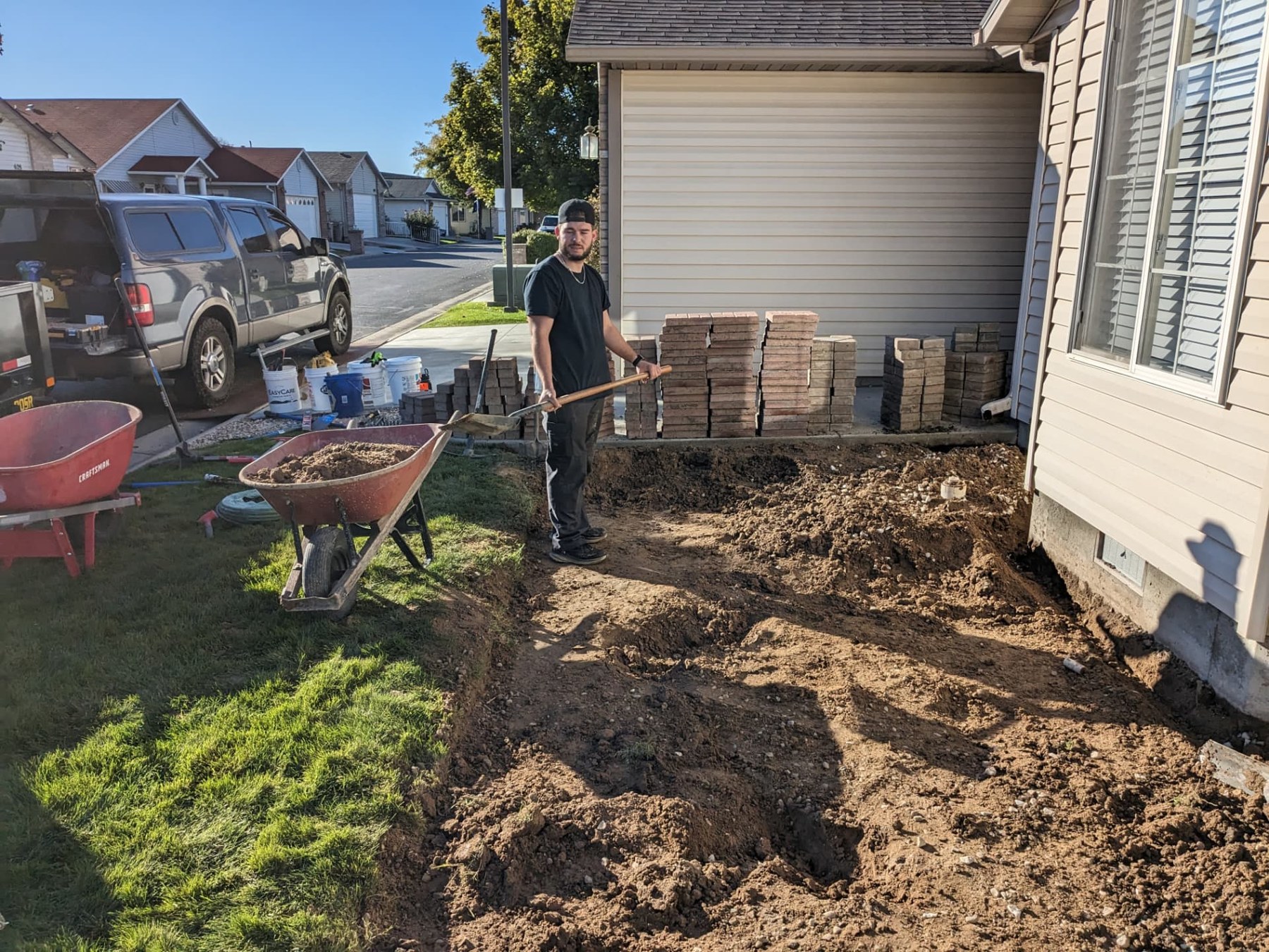 Crew preparing the ground for a patio beside a home