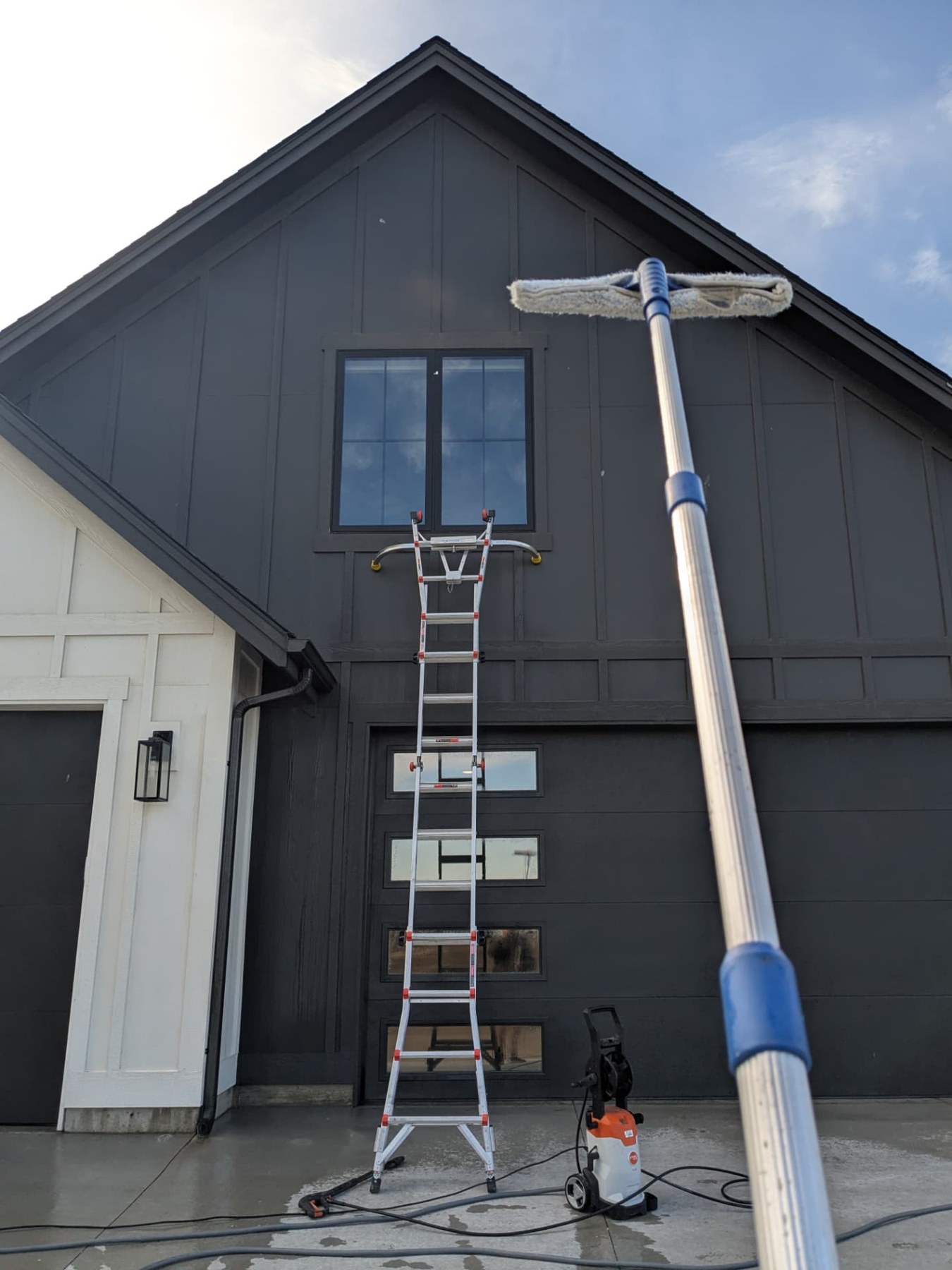 Ladder and extension pole set up for exterior maintenance on a two-story home