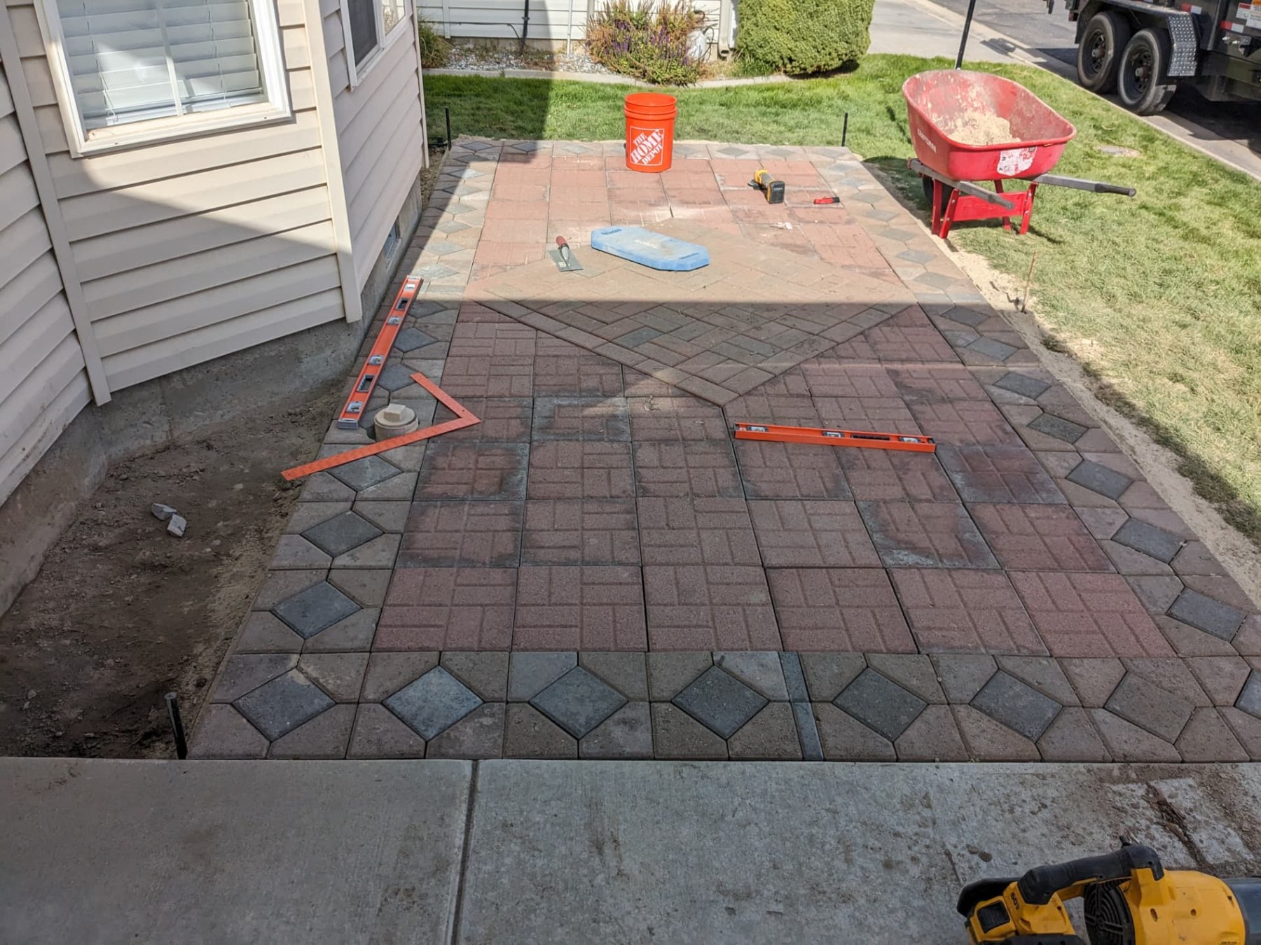 Patterned paver patio being installed beside a home