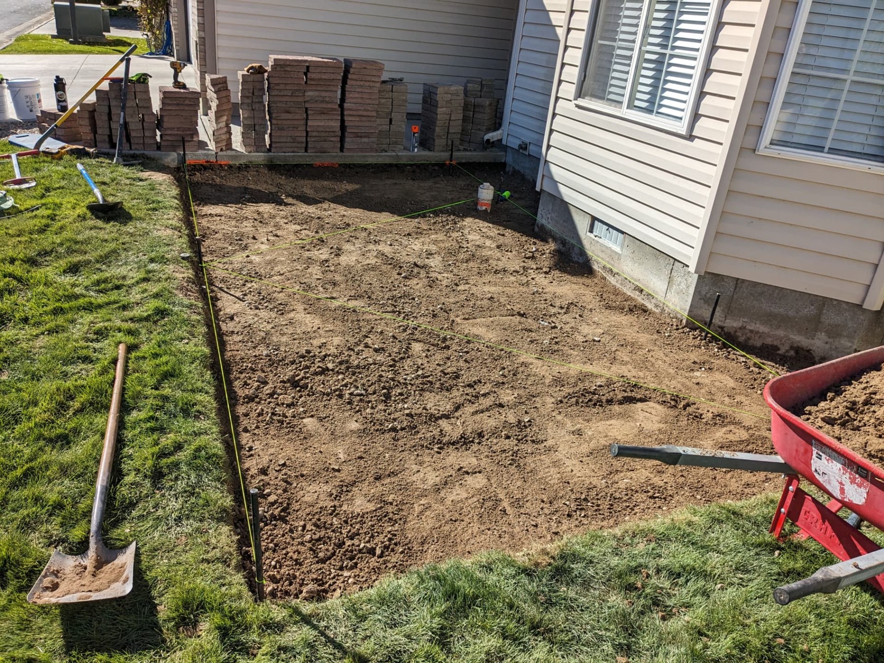 Excavated rectangular patio area with tools and materials nearby