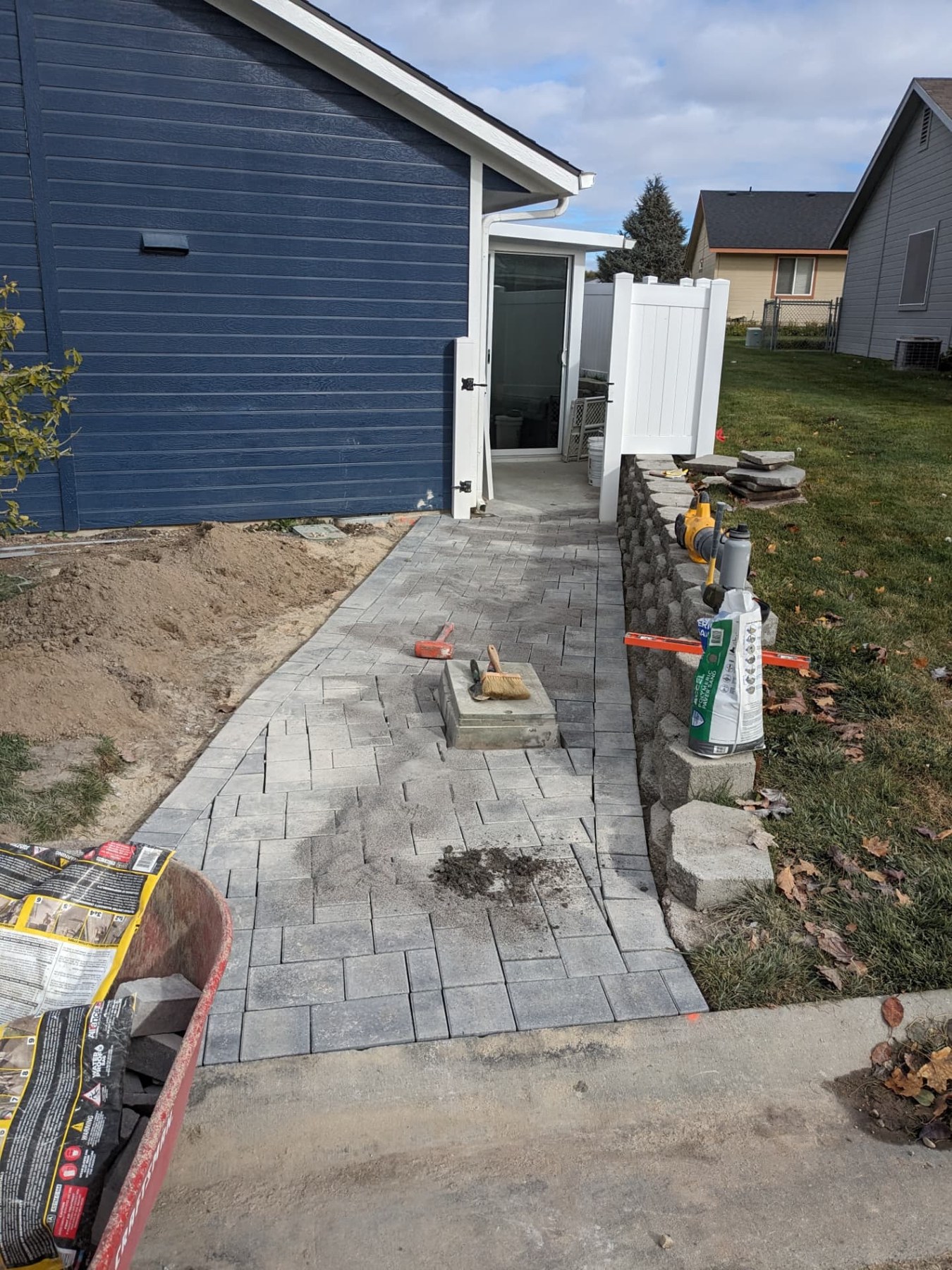 Completed gray paver entry walkway alongside a retaining wall