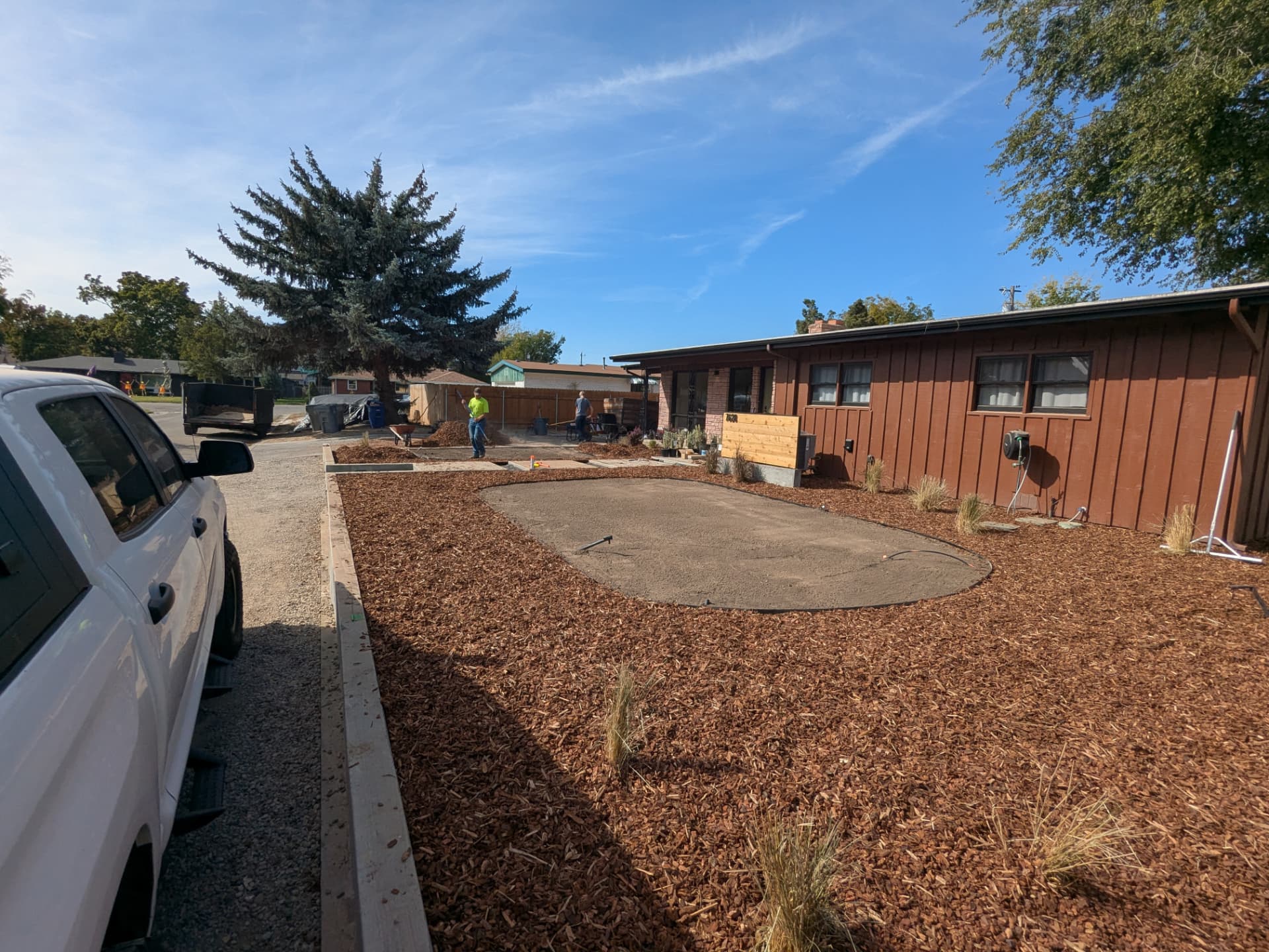 Mulch being installed in a landscape bed beside a work truck
