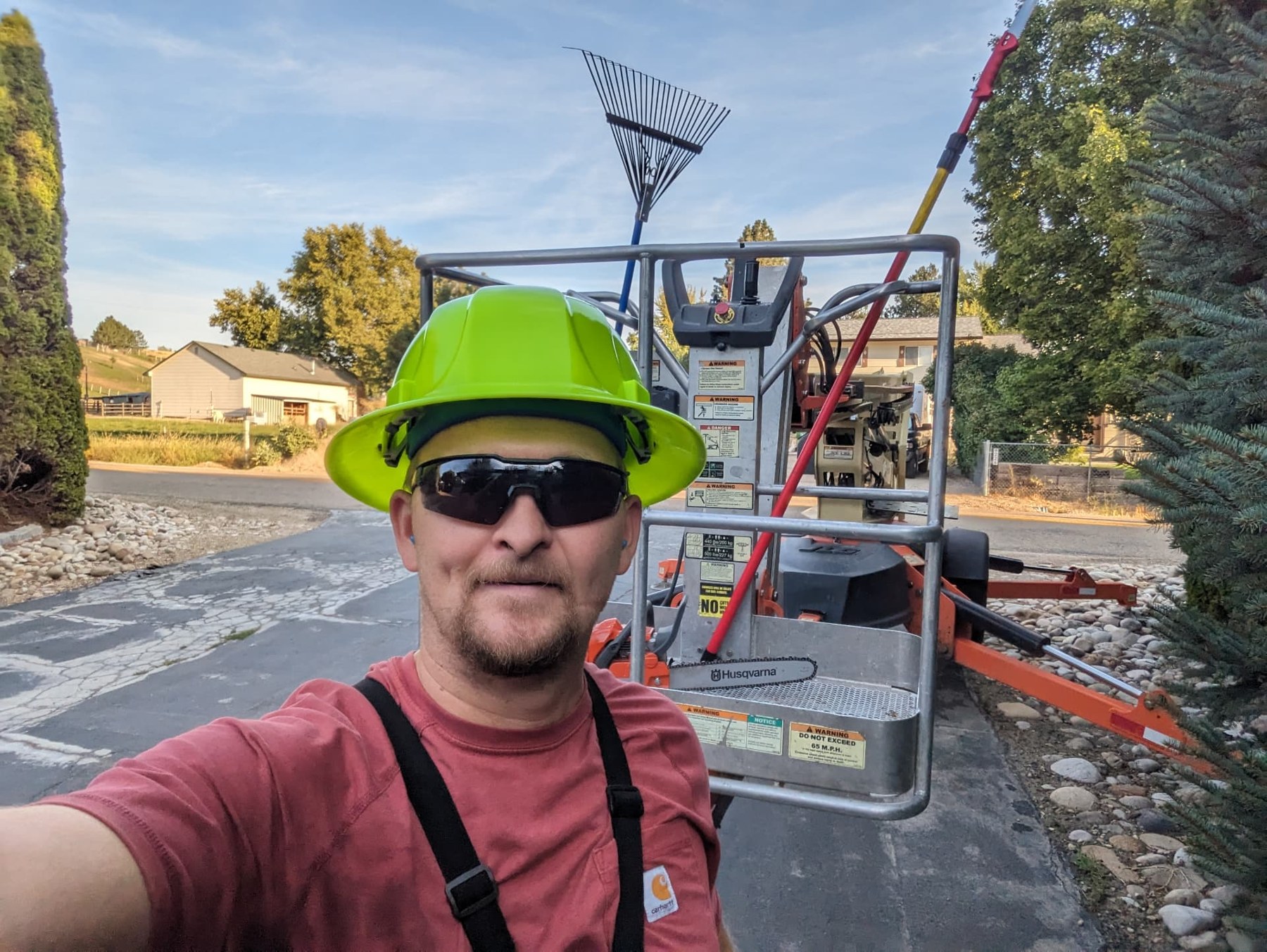 Crew member wearing a safety helmet beside tree service lift equipment