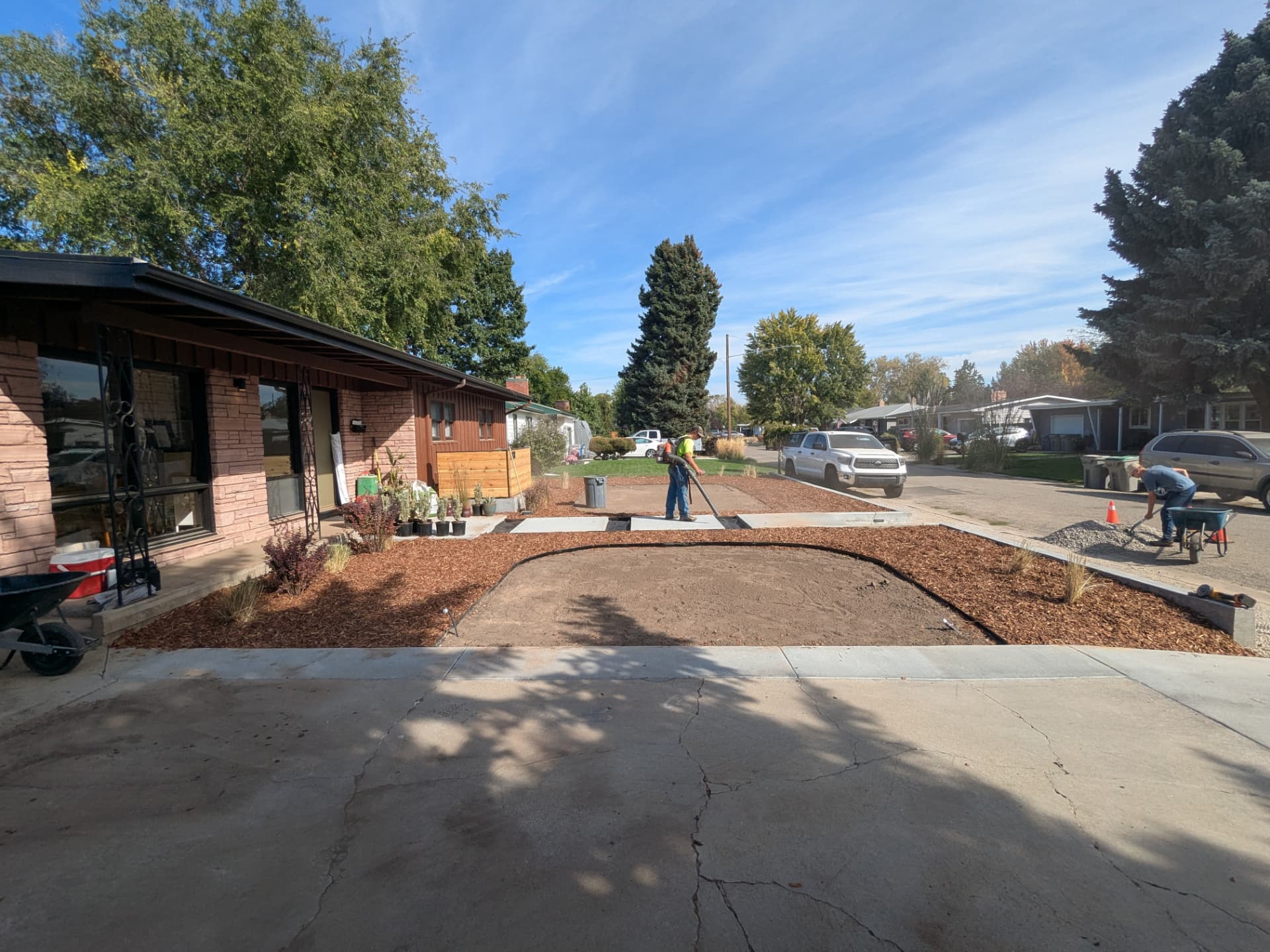 Crew using a leaf blower and wheelbarrow during a front yard cleanup