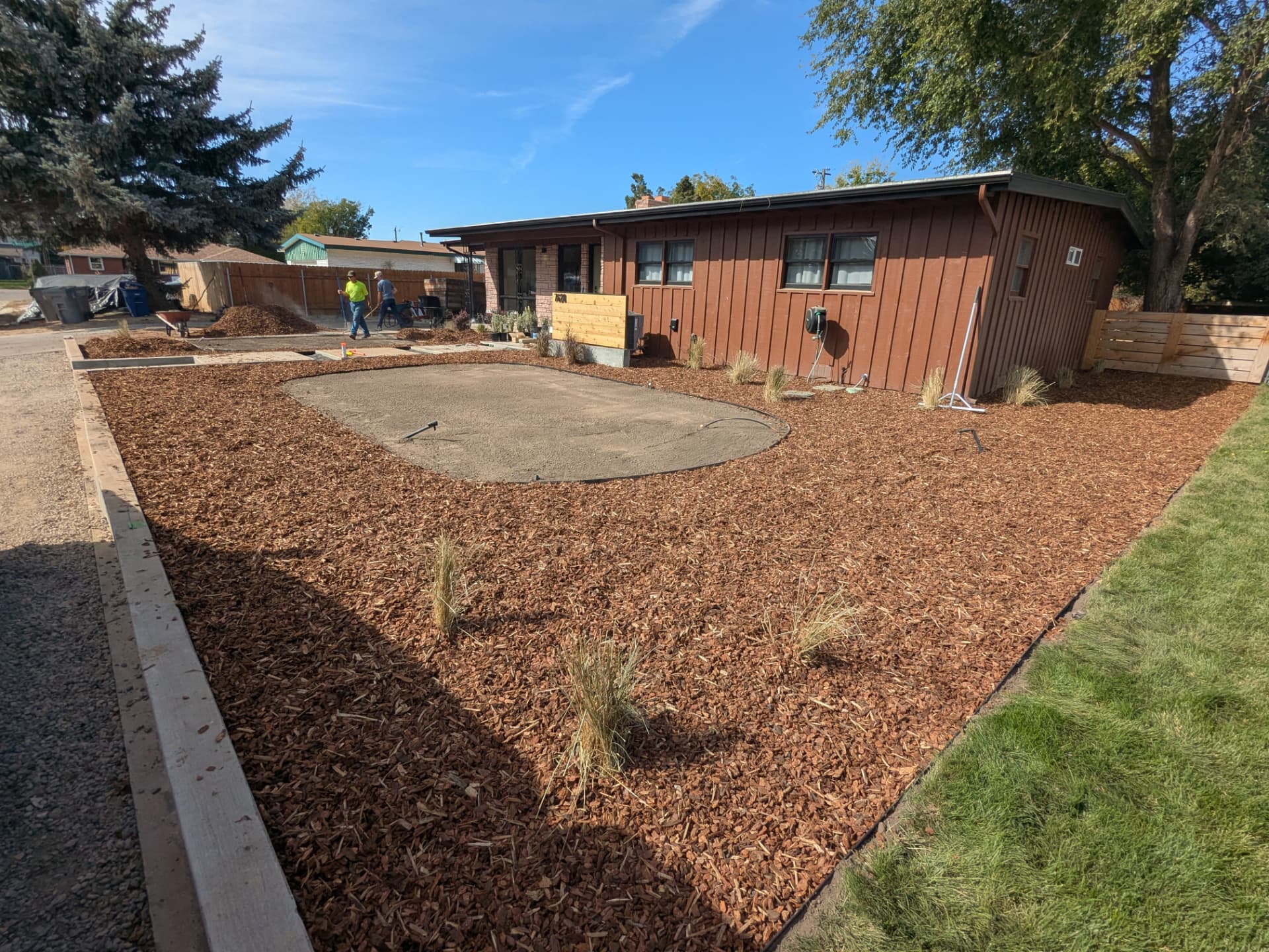 Finished mulch beds with ornamental grasses and cleared soil outside a home