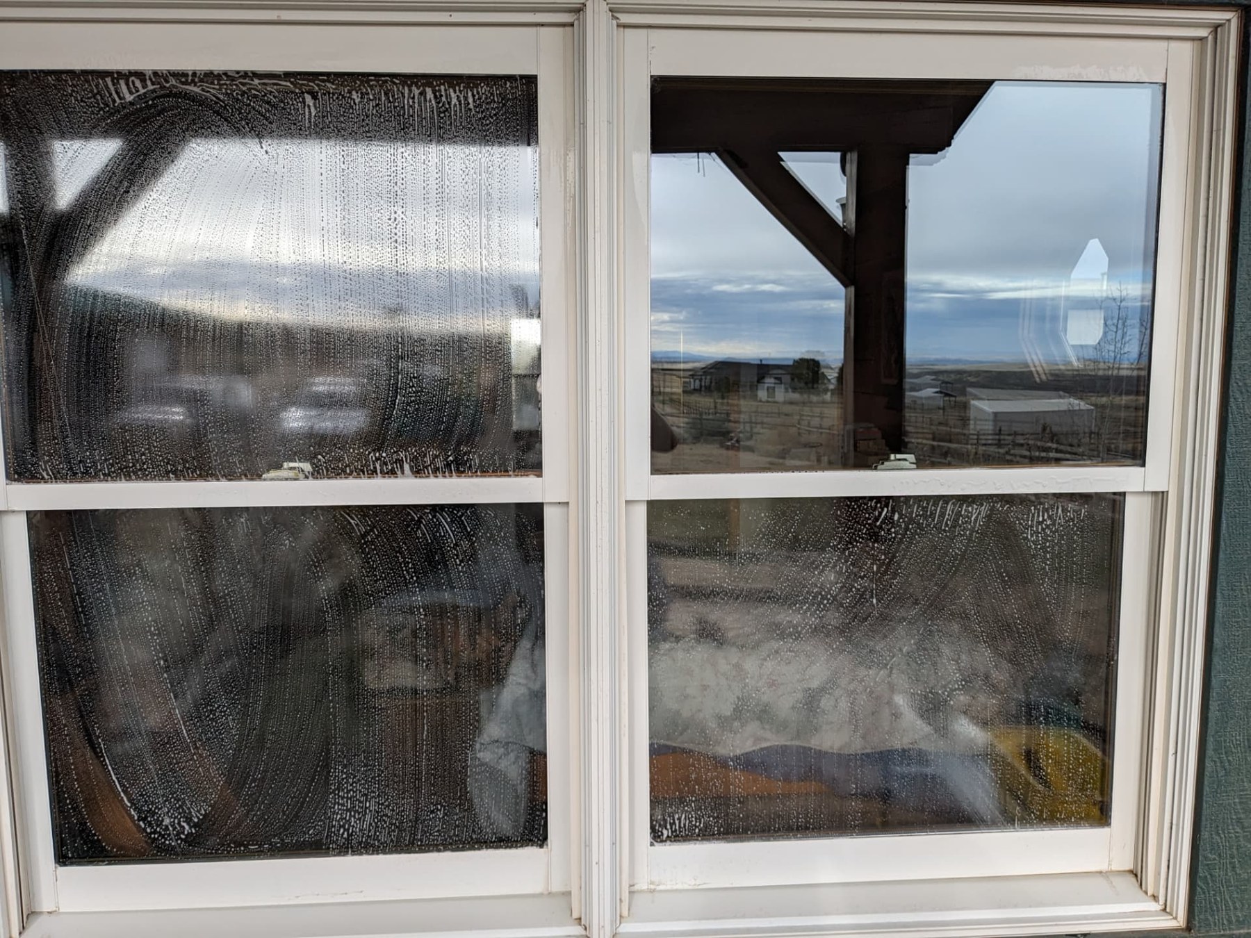 Residential window glass with visible buildup before cleaning