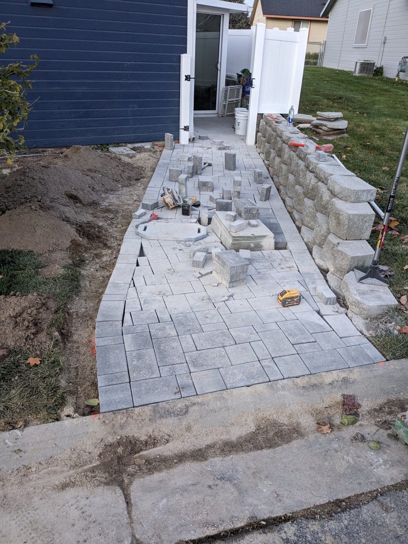 New paver walkway laid out beside a home with tools and materials