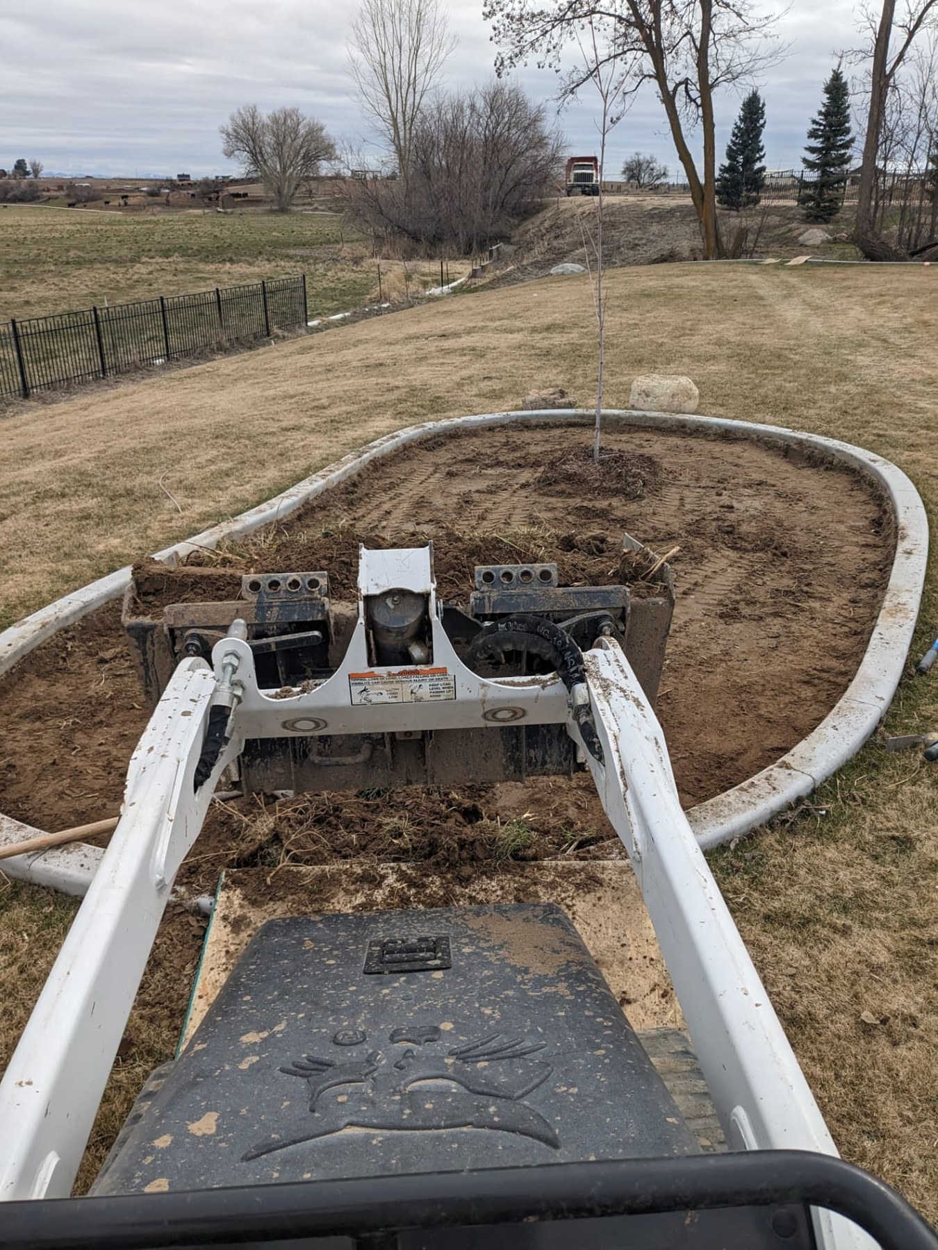 Compact loader beside a curved patio border during paver preparation