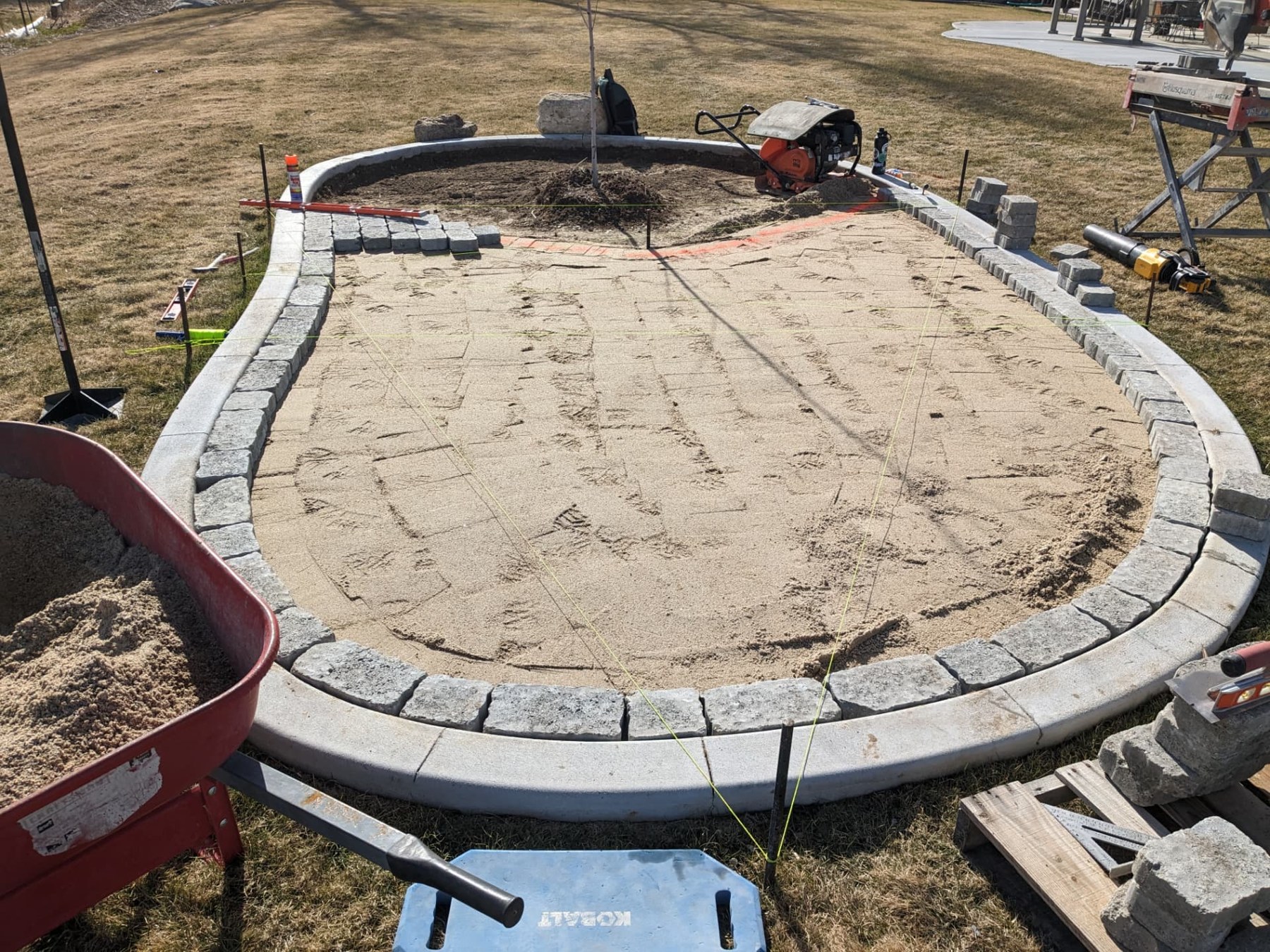 Sand base and curved paver border ready for patio installation