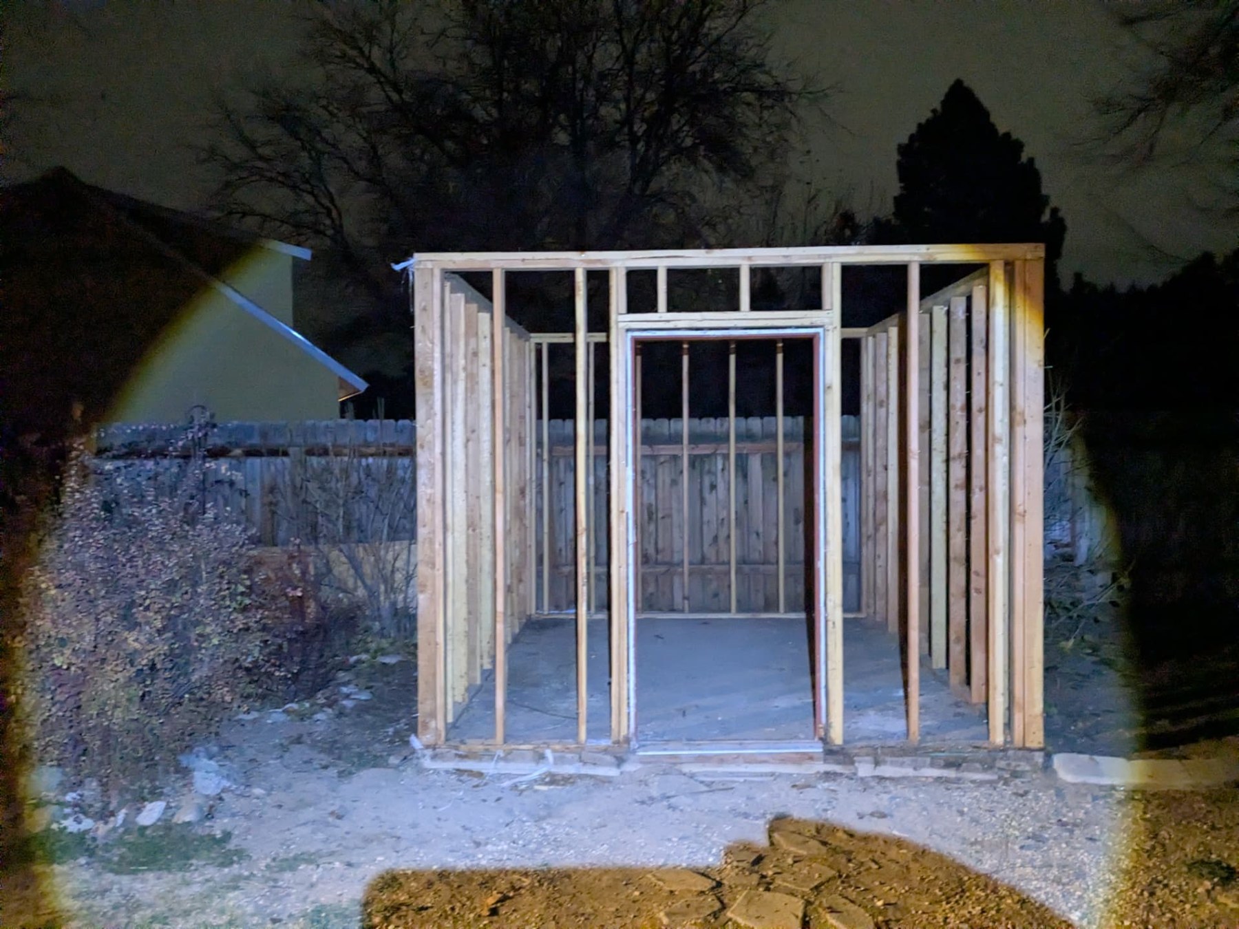 New wood framing for a backyard shed illuminated at night