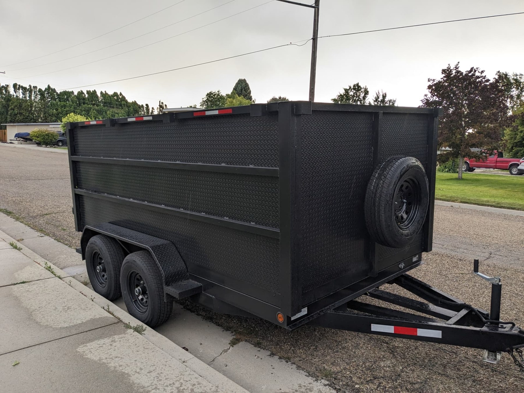 Black dump trailer parked beside a residential property