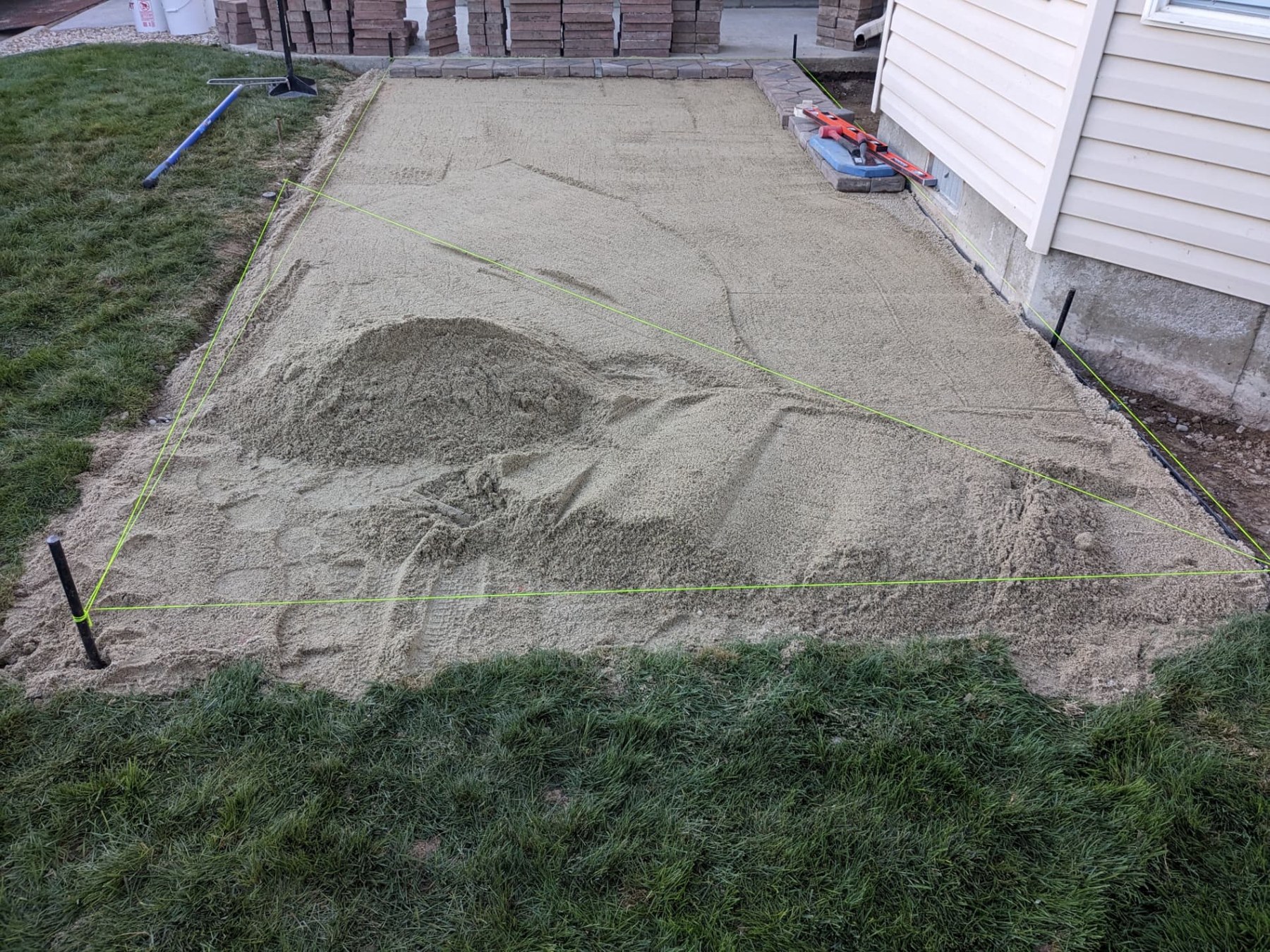 Sand base being leveled beside a home for paver installation
