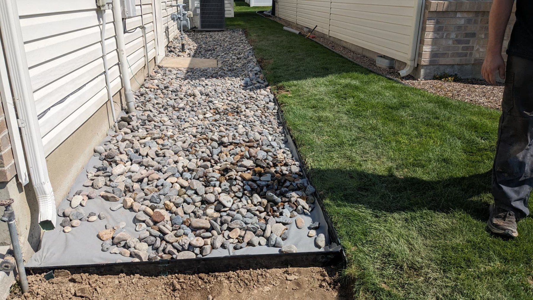 Finished river rock landscape bed beside a home and lawn