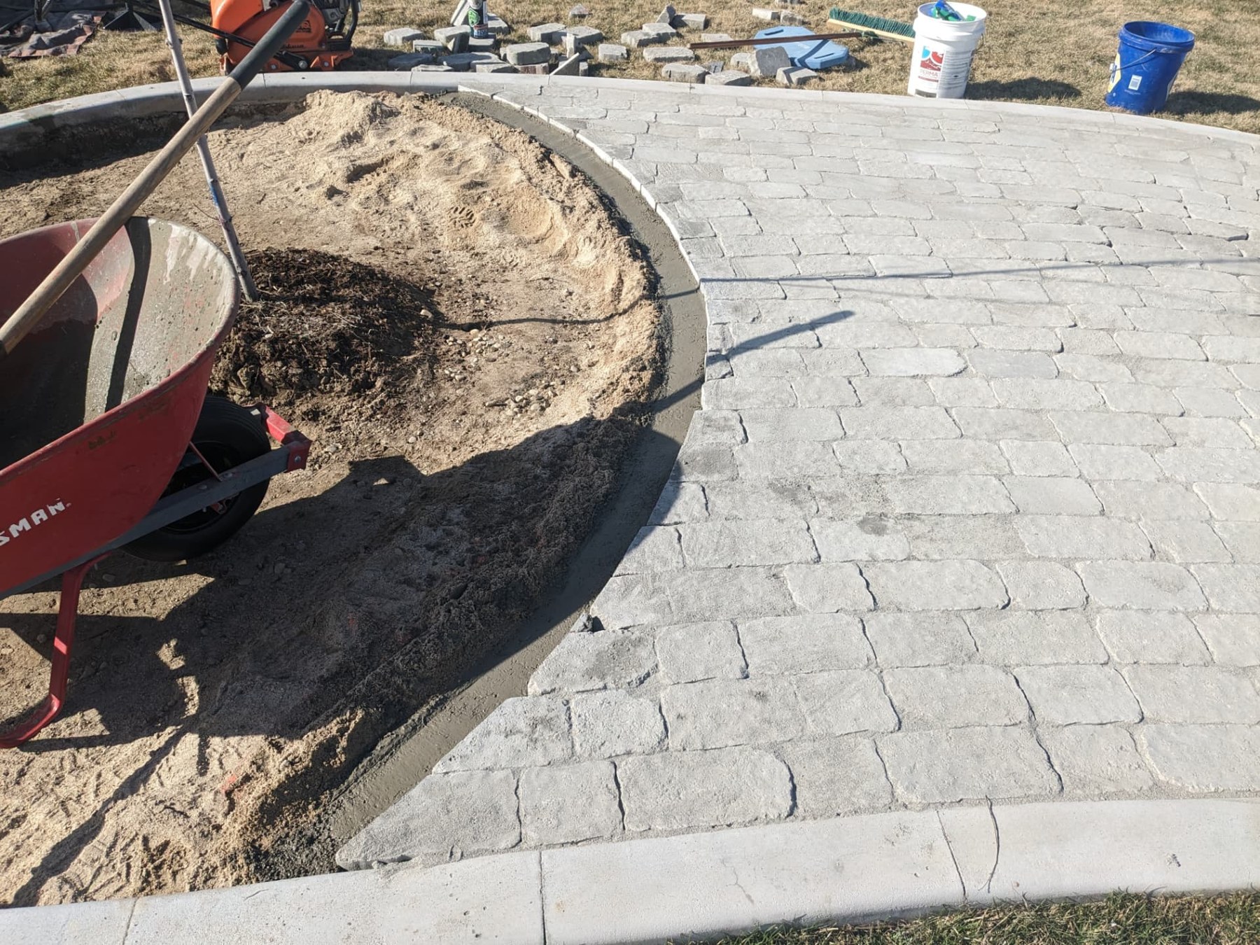 Gray paver walkway taking shape beside a curved planting bed