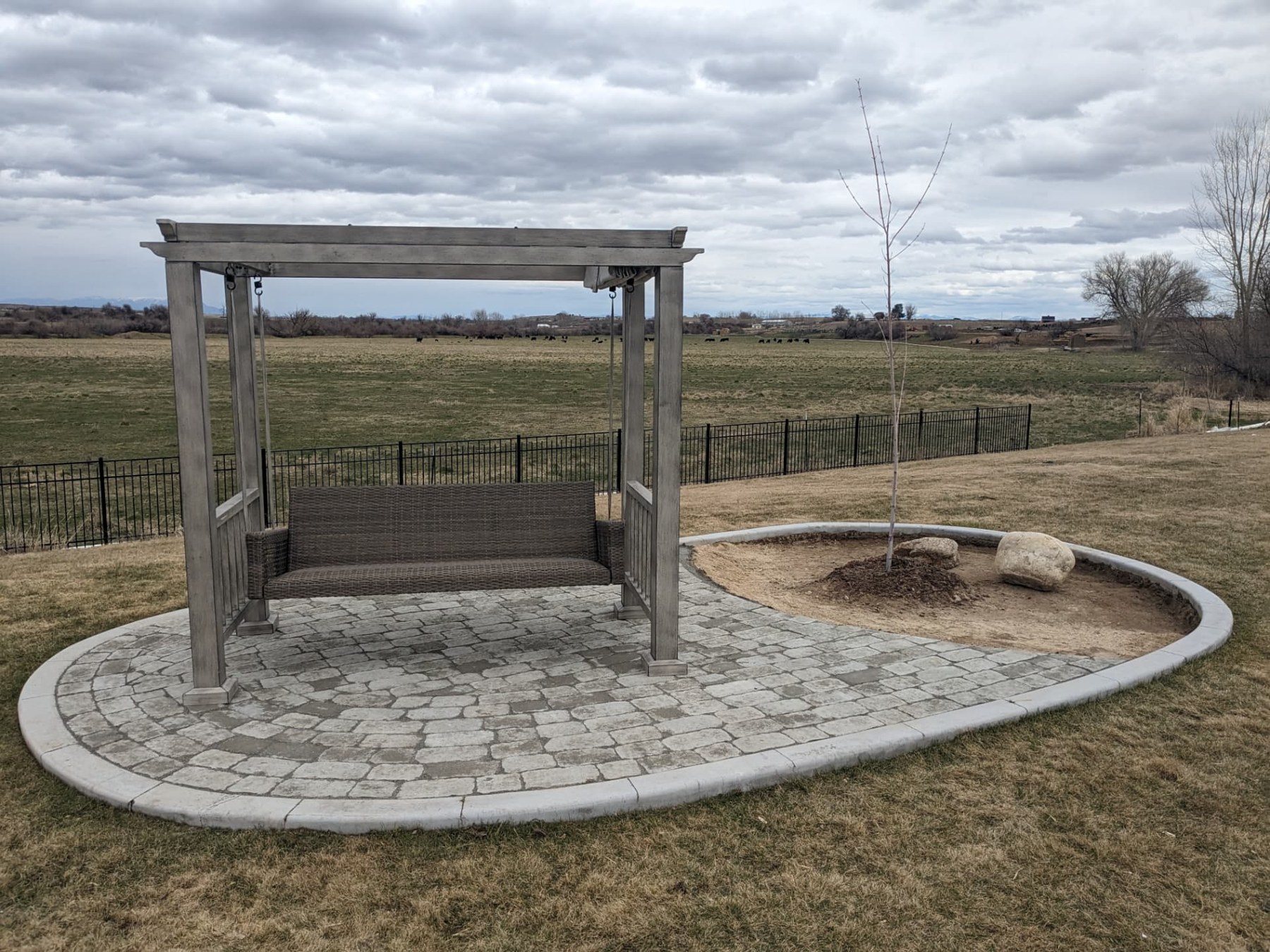Completed curved paver patio surrounding a backyard swing